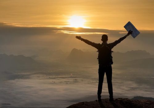 rear-view-hiker-standing-with-arms-outstretched-mountain-sunset_1048944-26020407